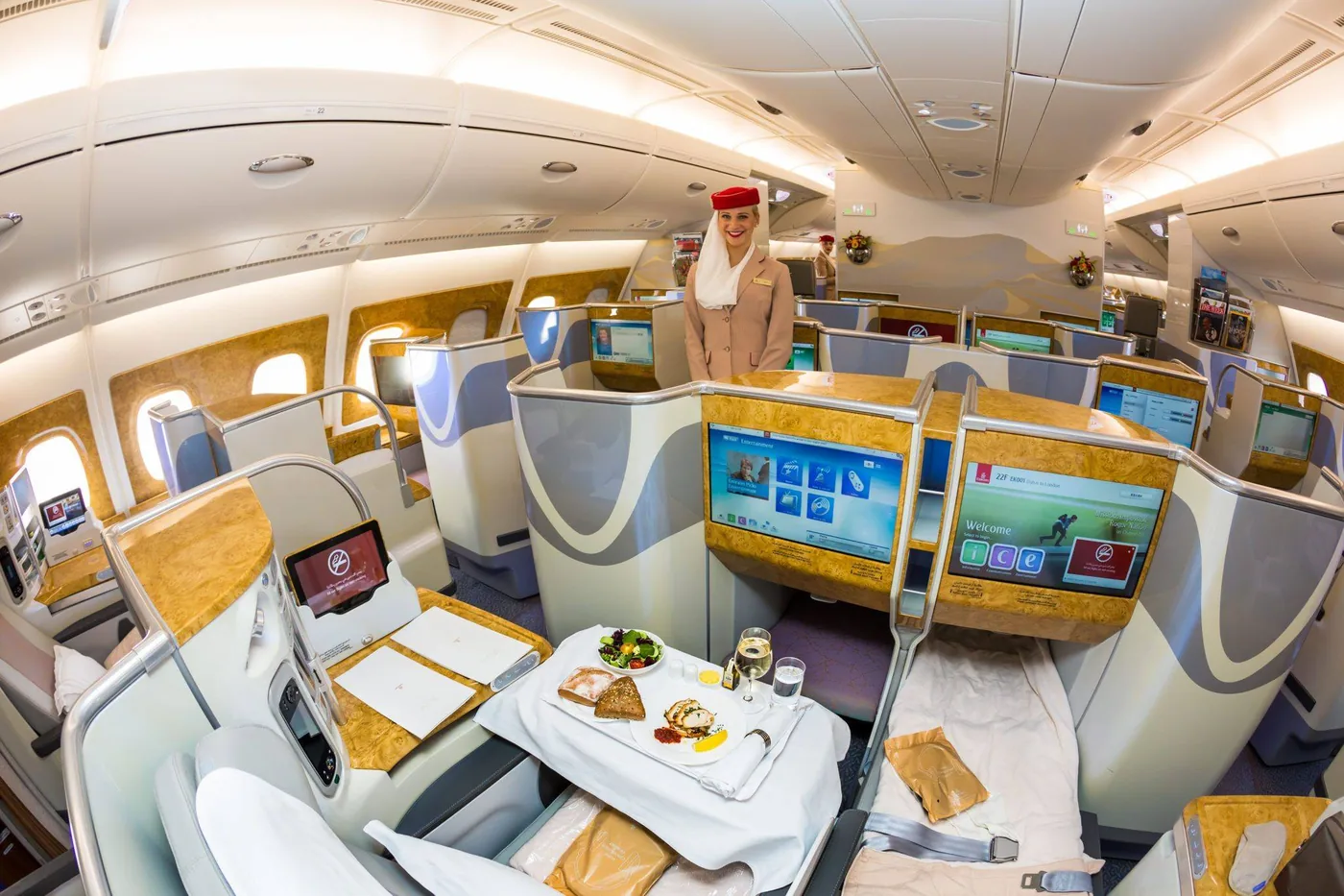 Кабина первого класса A380 Emirates с накрытым столом и бортпроводницей в проходе