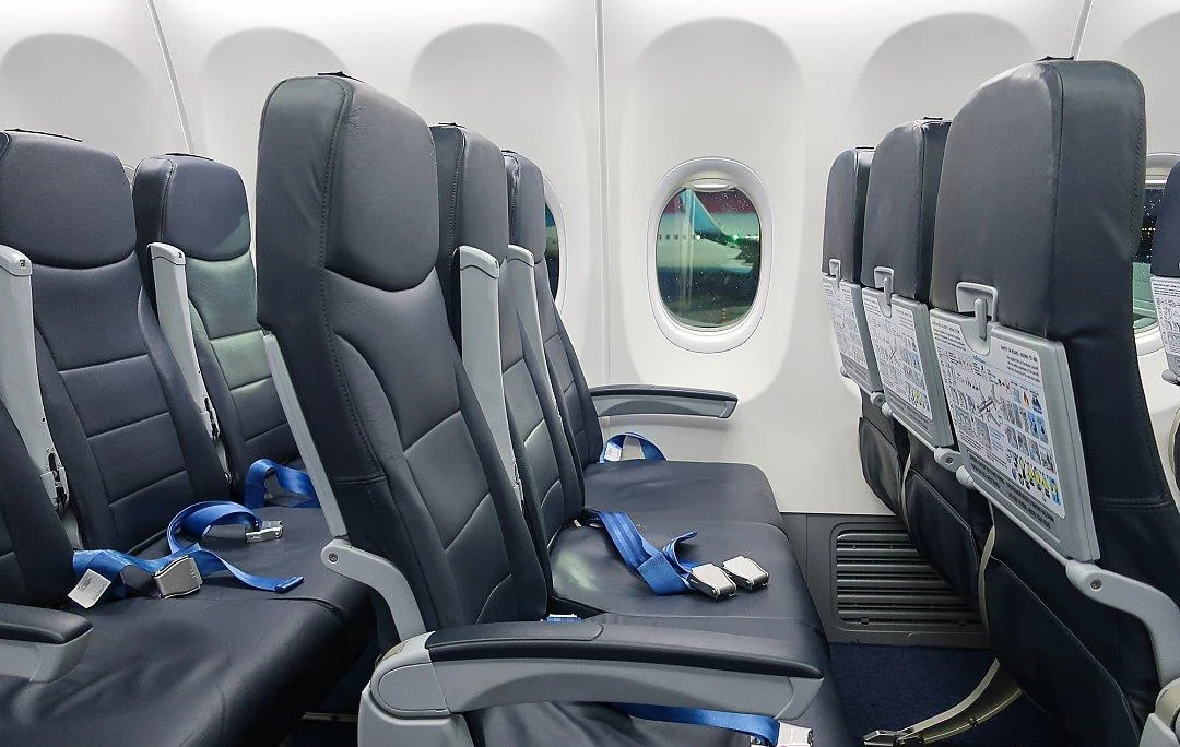 Кресла Boeing 737-800 «Победы»: тёмная кожа, синие ремни, рекламная плашка на спинке
