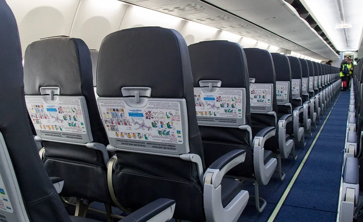 Салон Boeing 737-800 «Победы» вдоль прохода: ряды кожаных кресел уходят к хвосту