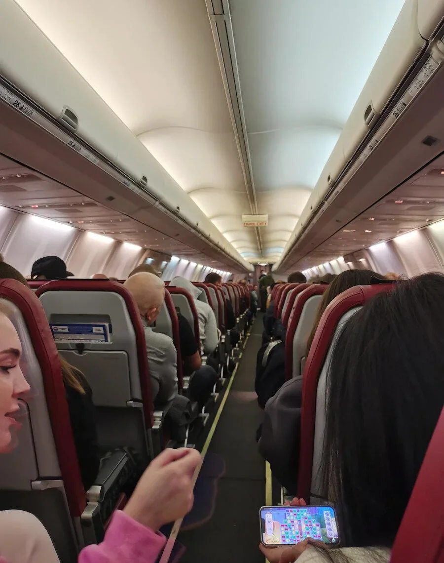 Вид вдоль прохода Boeing 737-900ER «Икара»: по три кресла с каждой стороны, 26-й ряд